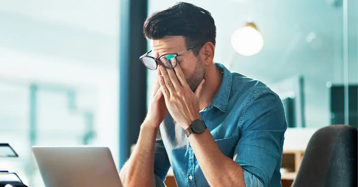 Man rubbing his eyes behind glasses