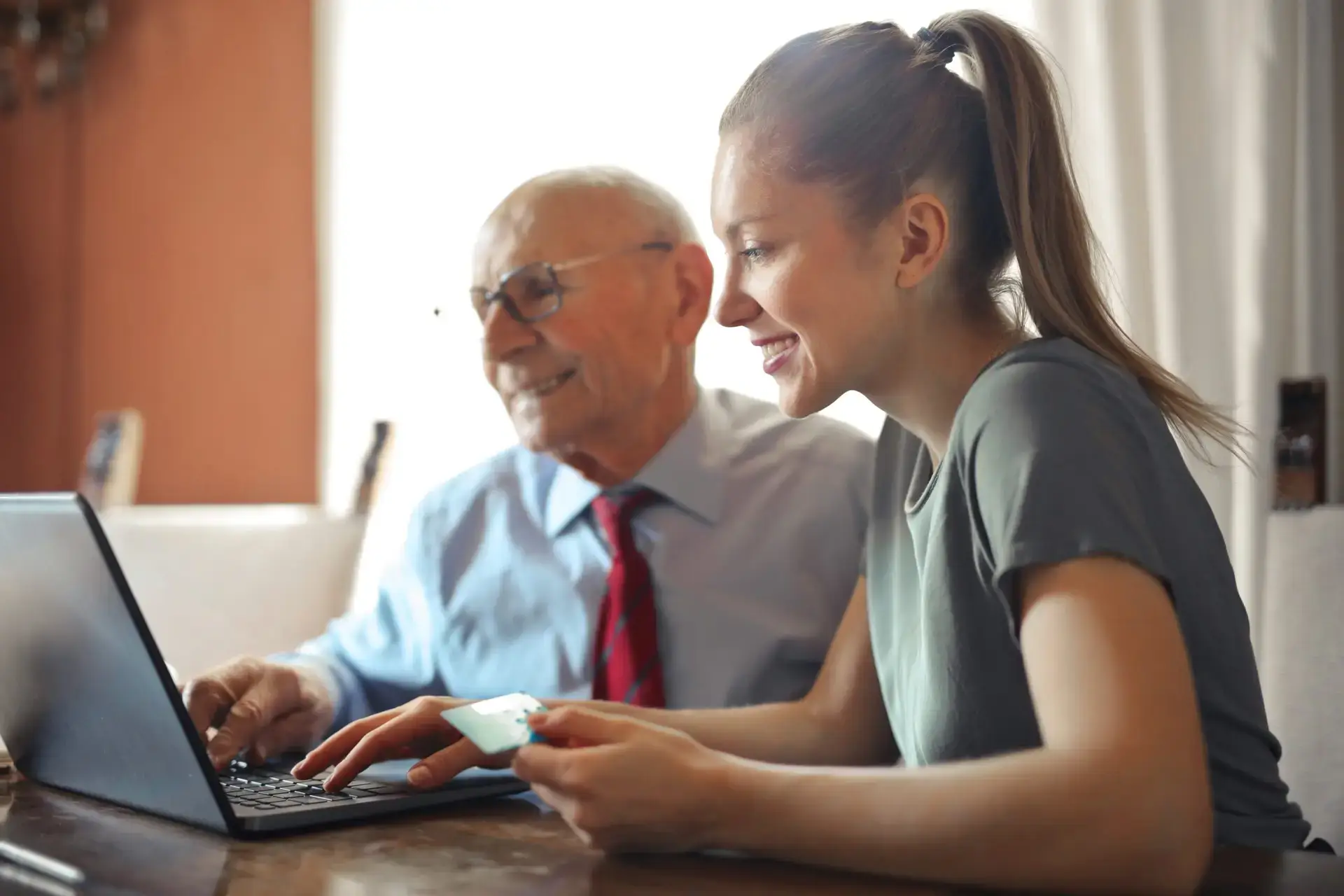 Young woman helping senior man with payment on internet