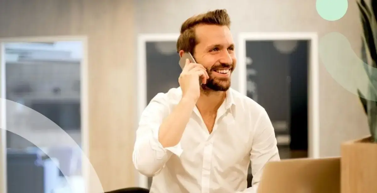 Guy with white shirt smiling and talking on a mobile phone.